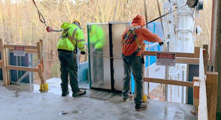 Larkin Hathawy employees guiding HVAC ducting into place on a job site
